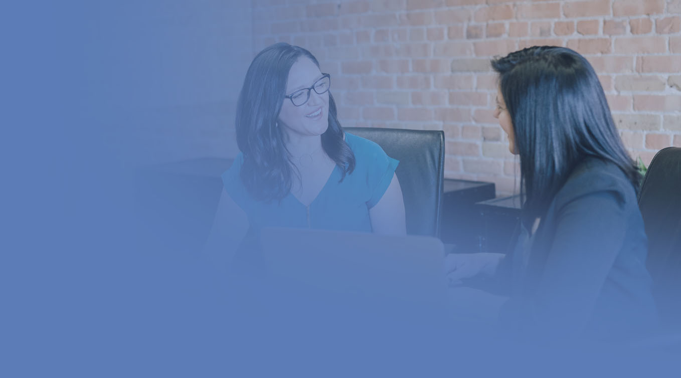 Two colleagues talking and smiling over a laptop